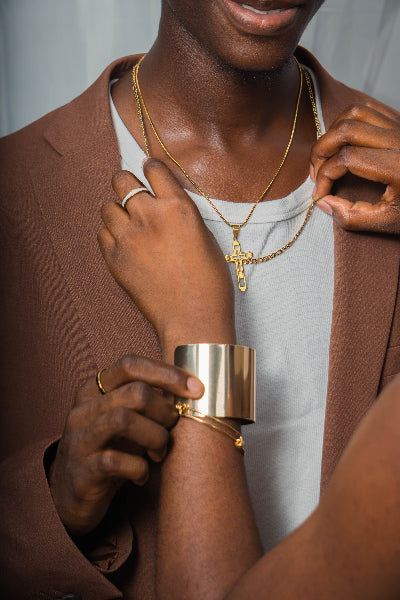 Couple  wearing gold jewellery including a cross necklace, bracelet, and ring.