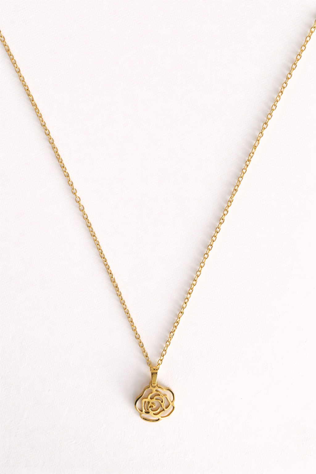 Gold necklace with a rose-shaped pendant on a white background